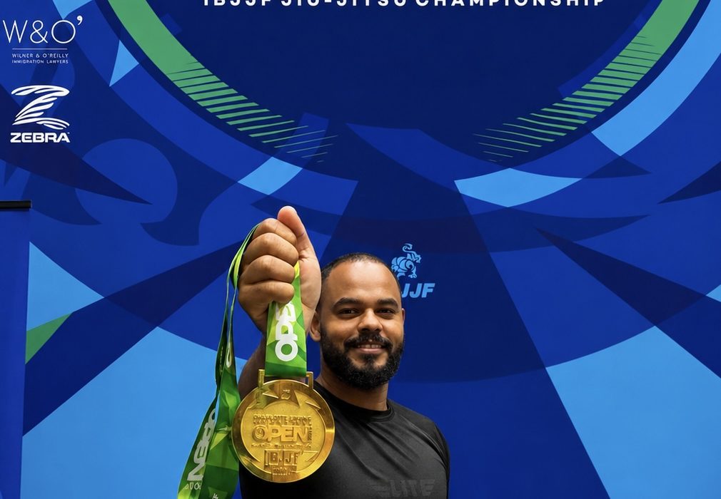 Marcos Aurelio segurando a medalha de ouro do No-Gi a frente, com o banner do Charlotte Spring International Open 2026 da IBJJF ao fundo