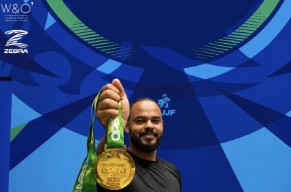 Marcos Aurelio segurando a medalha de ouro do No-Gi a frente, com o banner do Charlotte Spring International Open 2026 da IBJJF ao fundo