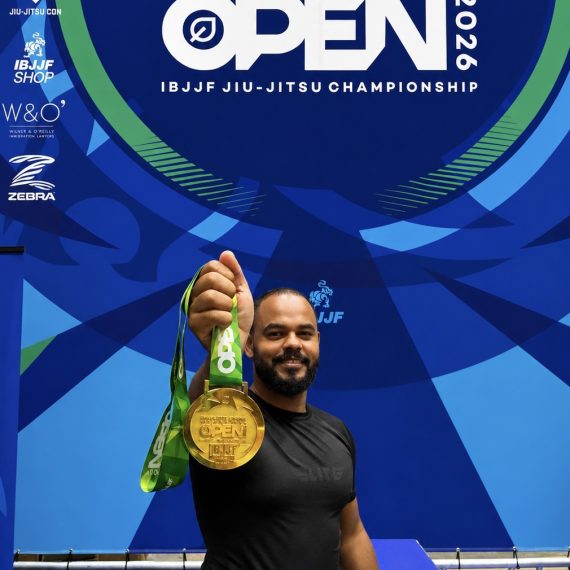 Marcos Aurelio segurando a medalha de ouro do No-Gi a frente, com o banner do Charlotte Spring International Open 2026 da IBJJF ao fundo