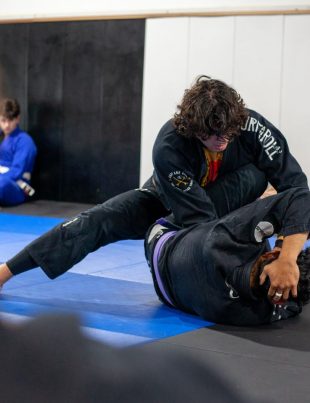 Praticantes de jiu-jitsu treinando posicoes de guarda no tatame