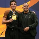 Tarcisio Damasceno Santos recebe a faixa preta ao lado do professor, com a medalha de ouro no pescoco