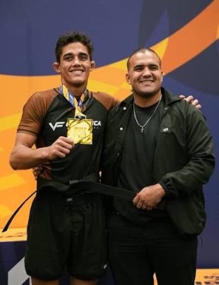 Tarcisio Damasceno Santos recebe a faixa preta ao lado do professor, com a medalha de ouro no pescoco