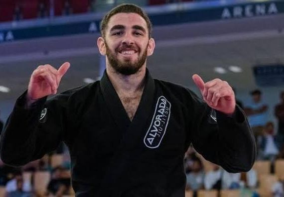Vinicius Liberati comemora com as maos erguidas de kimono preto da Alvorada Jiu-Jitsu