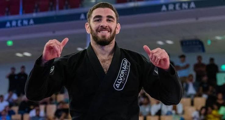 Vinicius Liberati comemora com as maos erguidas de kimono preto da Alvorada Jiu-Jitsu